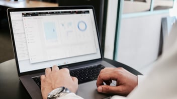 a man typing on a laptop with the screen showing analytics