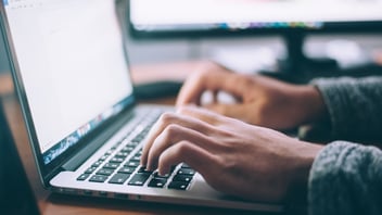 a pair of hands typing on a laptop