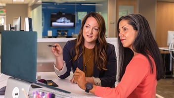 two women working and looking at a computer